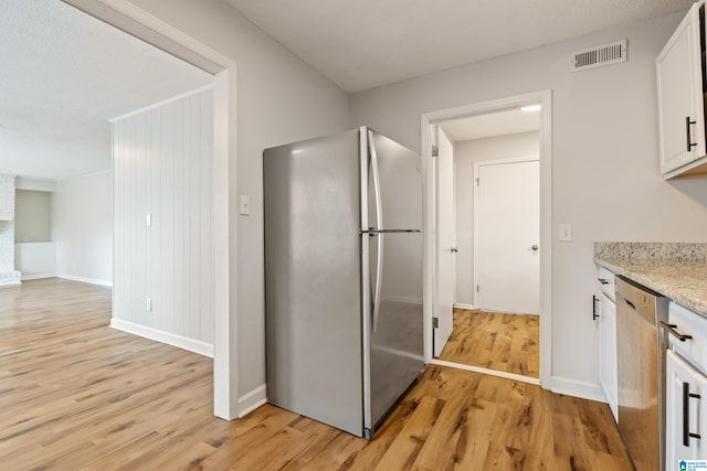 kitchen with stainless steel appliances, light hardwood / wood-style floors, white cabinets, and light stone counters