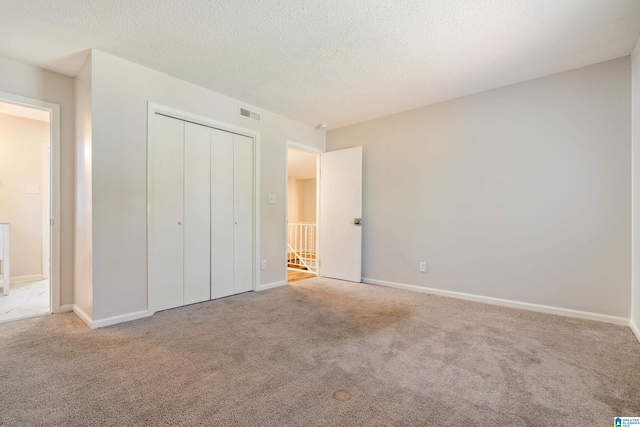 unfurnished bedroom featuring a closet, a textured ceiling, and light carpet