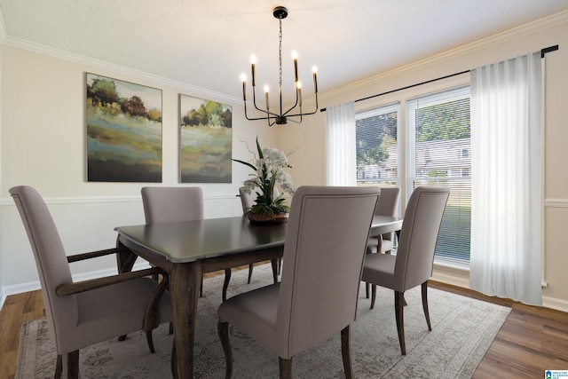 dining area with an inviting chandelier, wood-type flooring, ornamental molding, and a textured ceiling