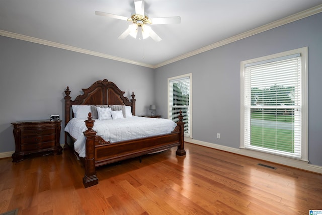 bedroom with hardwood / wood-style flooring, ceiling fan, multiple windows, and ornamental molding