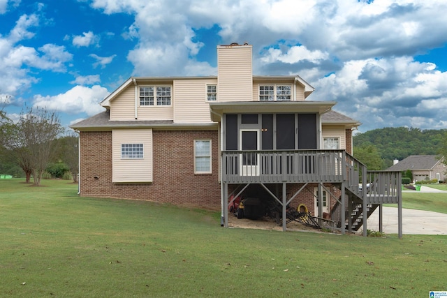 back of property featuring a lawn, a sunroom, and a wooden deck