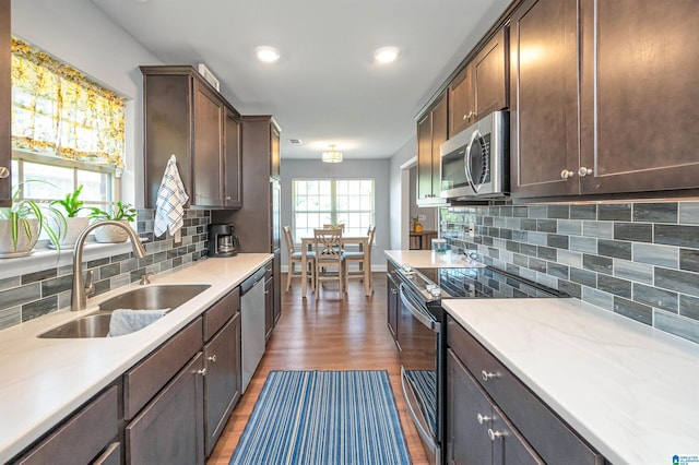 kitchen with hardwood / wood-style floors, sink, tasteful backsplash, dark brown cabinets, and appliances with stainless steel finishes