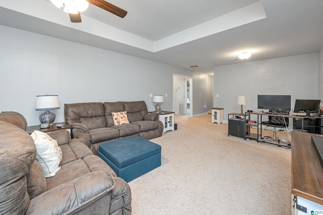 living room featuring a tray ceiling, carpet flooring, and ceiling fan