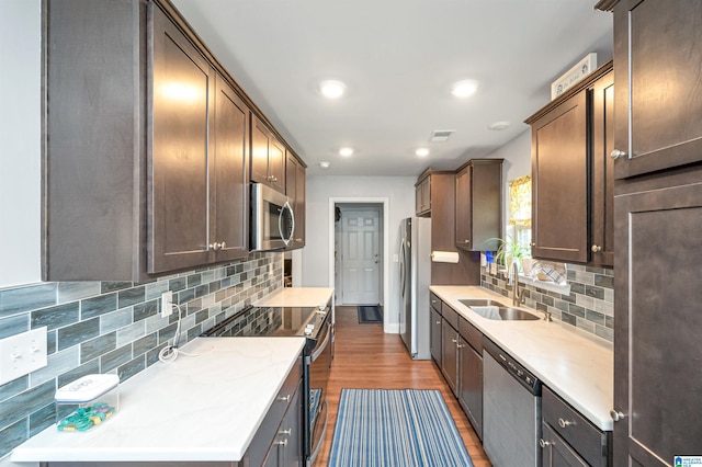 kitchen with hardwood / wood-style flooring, sink, appliances with stainless steel finishes, backsplash, and dark brown cabinets