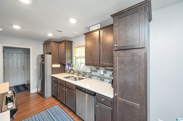 kitchen with appliances with stainless steel finishes, sink, dark brown cabinets, and light hardwood / wood-style floors