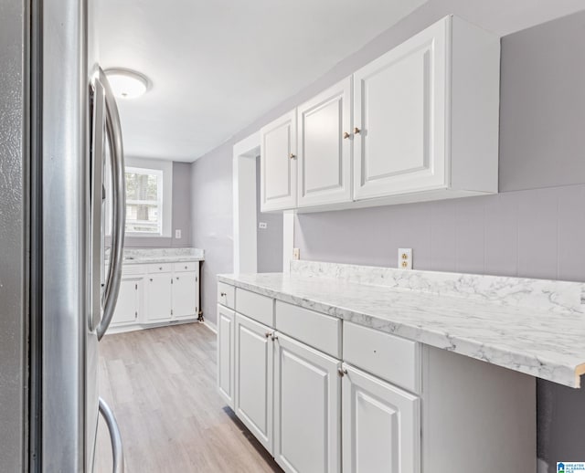 kitchen featuring white cabinetry, light hardwood / wood-style floors, and stainless steel refrigerator