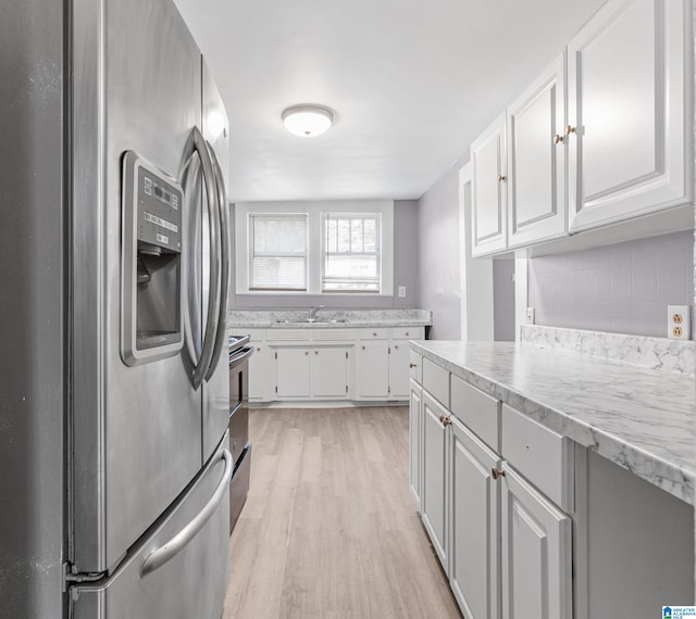 kitchen featuring stainless steel appliances, white cabinetry, sink, and light hardwood / wood-style flooring