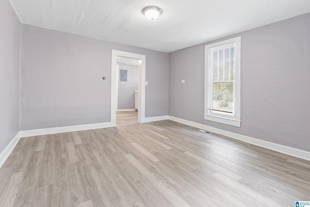 spare room with electric panel and light hardwood / wood-style flooring