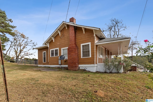 rear view of house featuring a porch and a lawn