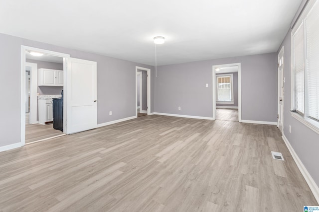 unfurnished living room featuring plenty of natural light and light hardwood / wood-style flooring