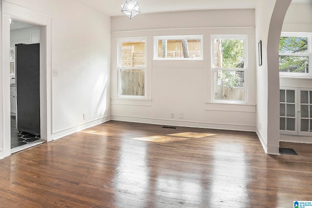 spare room with a wealth of natural light and dark hardwood / wood-style floors