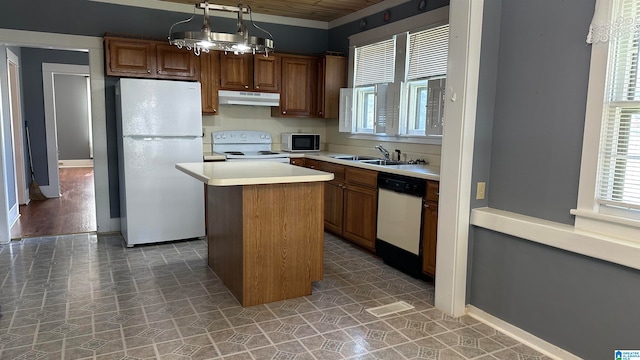 kitchen with sink, hanging light fixtures, white appliances, a chandelier, and a kitchen island