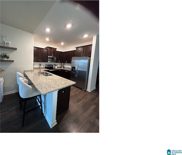 kitchen with appliances with stainless steel finishes, sink, a kitchen breakfast bar, dark wood-type flooring, and kitchen peninsula