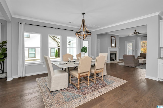 dining space featuring dark wood-type flooring, ceiling fan with notable chandelier, and ornamental molding