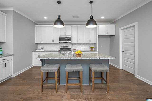 kitchen with appliances with stainless steel finishes, a center island with sink, and white cabinetry