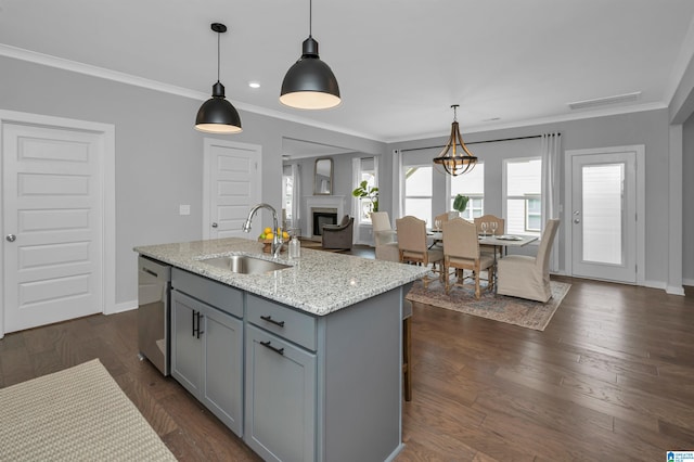 kitchen with dishwasher, dark wood-type flooring, sink, an island with sink, and decorative light fixtures