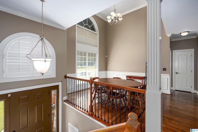 foyer featuring dark hardwood / wood-style flooring, a chandelier, crown molding, and decorative columns