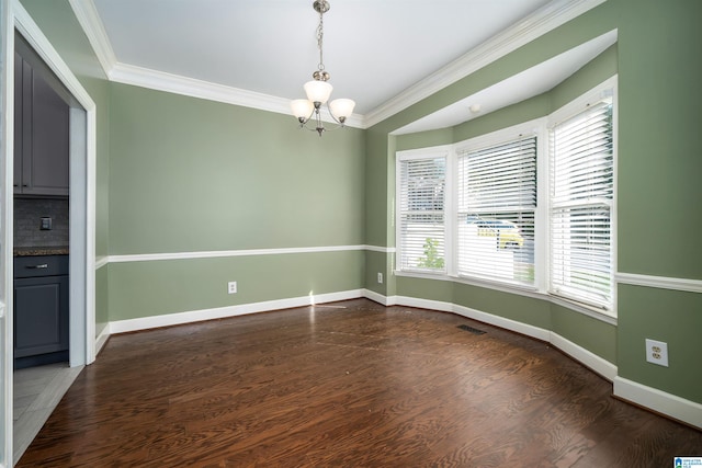 empty room with dark hardwood / wood-style flooring, a chandelier, and crown molding