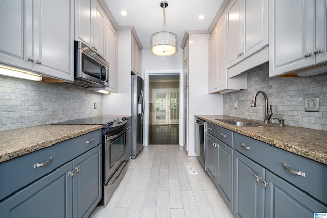 kitchen featuring stainless steel appliances, dark stone counters, decorative light fixtures, decorative backsplash, and sink