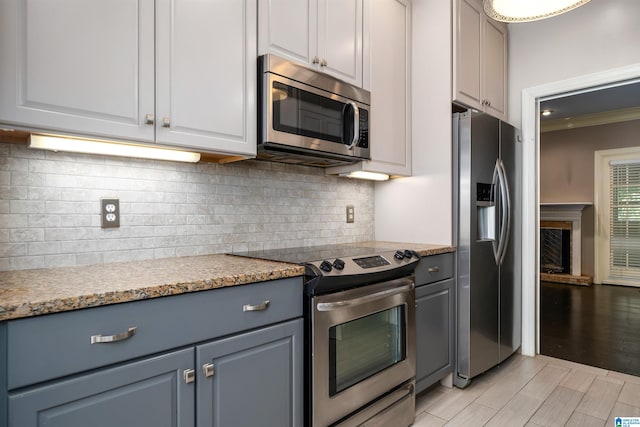 kitchen featuring appliances with stainless steel finishes, light hardwood / wood-style flooring, white cabinets, gray cabinets, and decorative backsplash