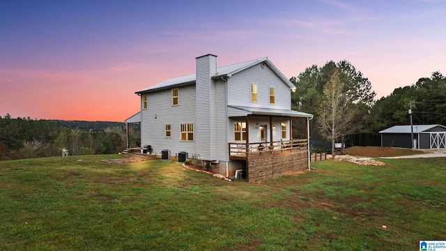 back house at dusk featuring central AC unit and a yard