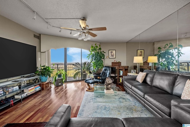 living room featuring ceiling fan, wood-type flooring, a textured ceiling, and rail lighting