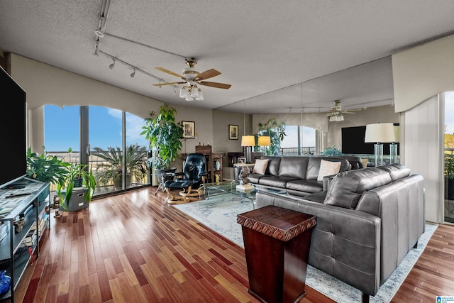 living room with a textured ceiling, wood-type flooring, ceiling fan, and plenty of natural light