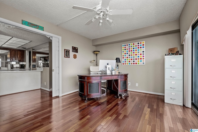 home office featuring dark wood-type flooring, ceiling fan, and a textured ceiling