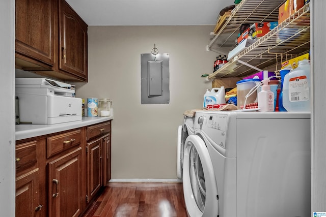 clothes washing area featuring dark wood-type flooring, washing machine and dryer, cabinets, and electric panel