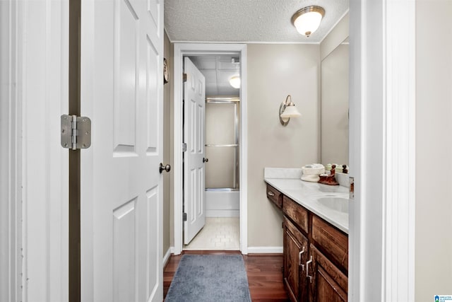 bathroom featuring hardwood / wood-style floors, enclosed tub / shower combo, vanity, and a textured ceiling