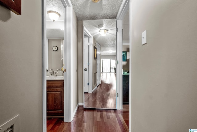 hallway featuring dark hardwood / wood-style flooring, a textured ceiling, and sink