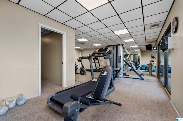 exercise area featuring a paneled ceiling and light colored carpet