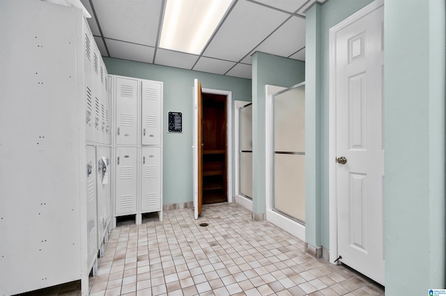 bathroom with a shower with shower door, tile patterned floors, and a drop ceiling