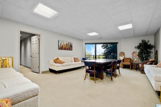 dining area featuring a paneled ceiling and light carpet