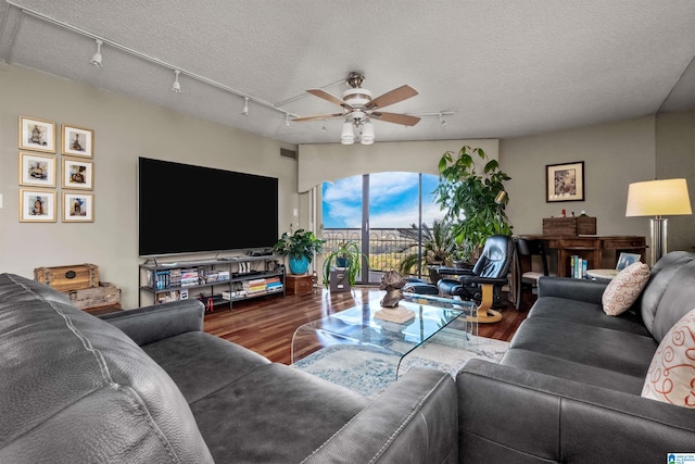 living room with a textured ceiling, track lighting, hardwood / wood-style flooring, and ceiling fan