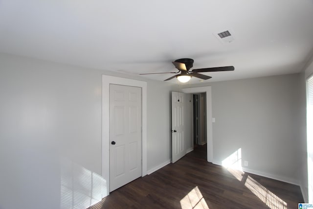 unfurnished bedroom featuring ceiling fan, dark hardwood / wood-style floors, and a closet