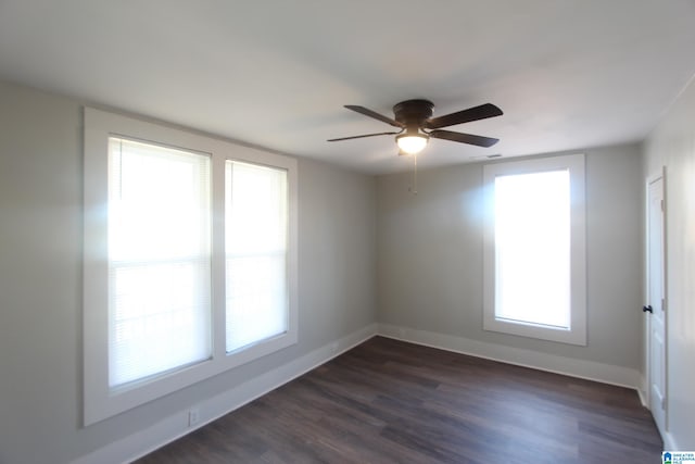 empty room featuring dark wood-type flooring, a healthy amount of sunlight, and ceiling fan