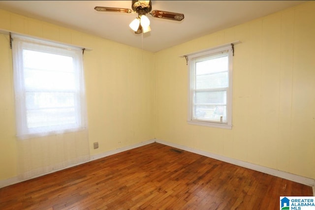 unfurnished room with hardwood / wood-style floors, a wealth of natural light, and ceiling fan