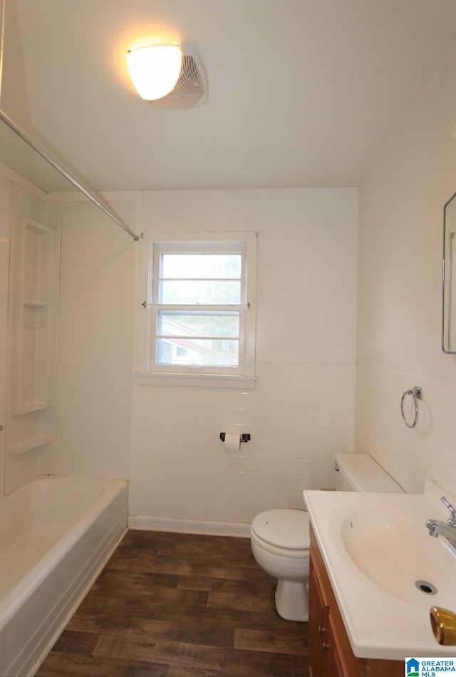 full bathroom with  shower combination, wood-type flooring, vanity, toilet, and tile walls