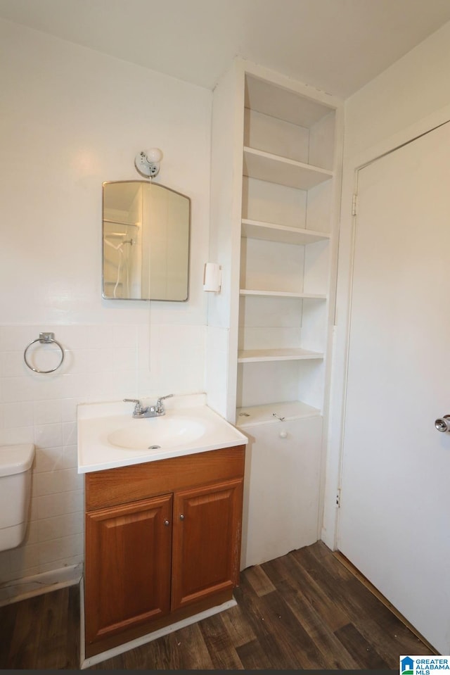 bathroom with built in shelves, tile walls, vanity, hardwood / wood-style floors, and toilet