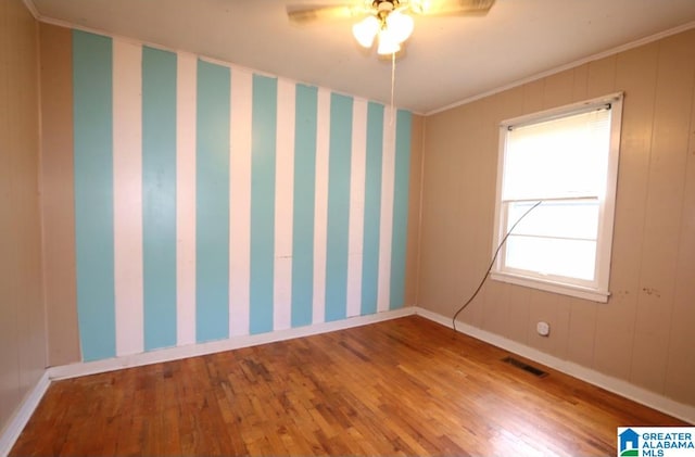 empty room featuring crown molding, hardwood / wood-style flooring, and ceiling fan