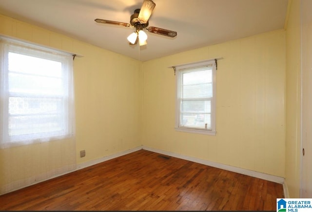 unfurnished room with plenty of natural light, wood-type flooring, and ceiling fan