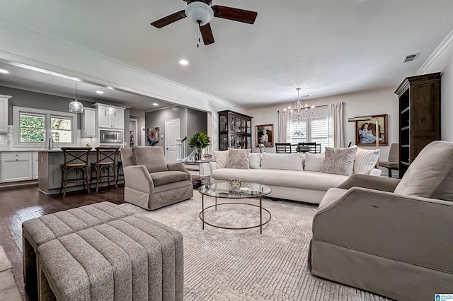 living room featuring ceiling fan with notable chandelier, dark hardwood / wood-style floors, crown molding, and sink