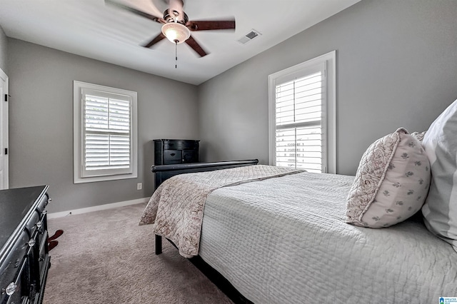 bedroom with light colored carpet, multiple windows, and ceiling fan