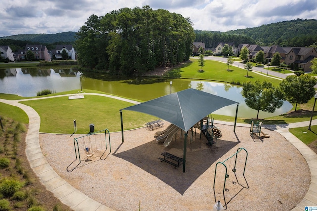 view of home's community featuring a water and mountain view, a playground, and a yard