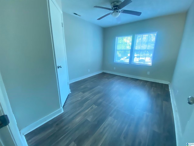 empty room featuring dark wood-type flooring and ceiling fan