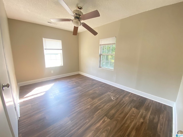 unfurnished room featuring ceiling fan, a textured ceiling, a healthy amount of sunlight, and dark hardwood / wood-style floors