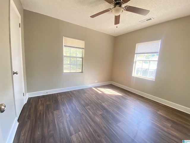 empty room featuring ceiling fan, plenty of natural light, a textured ceiling, and dark hardwood / wood-style flooring