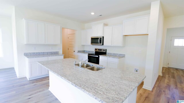 kitchen featuring appliances with stainless steel finishes, an island with sink, and white cabinets