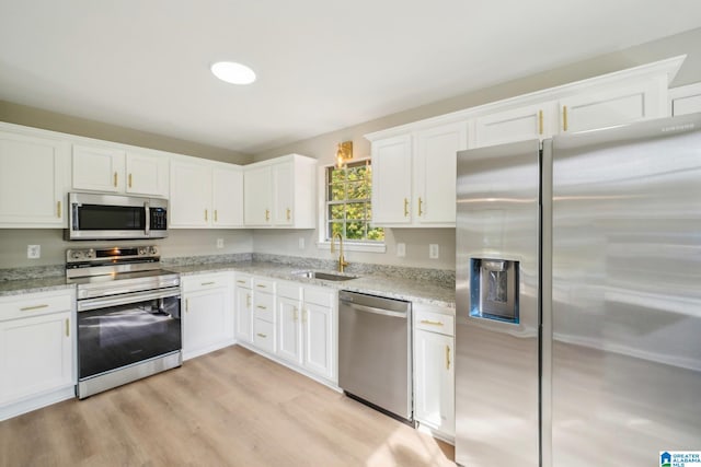 kitchen featuring light wood-type flooring, appliances with stainless steel finishes, light stone countertops, sink, and white cabinets